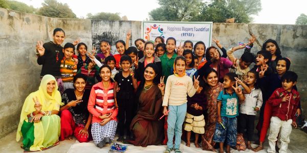 Group of children and adults happily posing with peace signs outdoors.