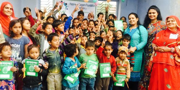 Group of children and women celebrating at a community event holding booklets.